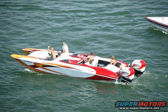 Red and white speedboats with people on board, one with dual outboard motors