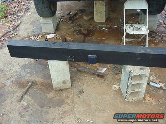 black metal bumper on cinder blocks, tire visible above