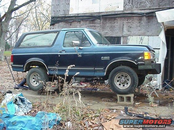 Blue Ford F-150 Bronco on cinder blocks, side view, with F-150 badging visible