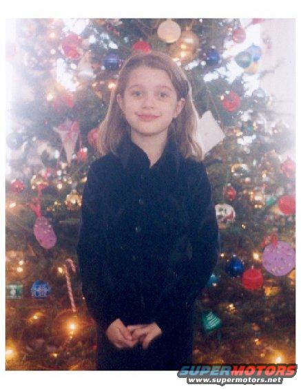 Young child stands in front of a decorated Christmas tree