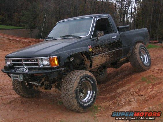 Black lifted Toyota pickup truck with off-road tires on a dirt trail