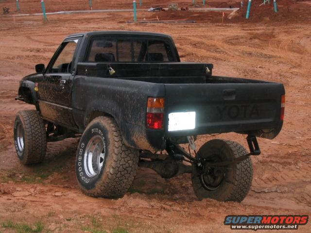 black Toyota pickup truck with lifted suspension and off-road tires, rear view