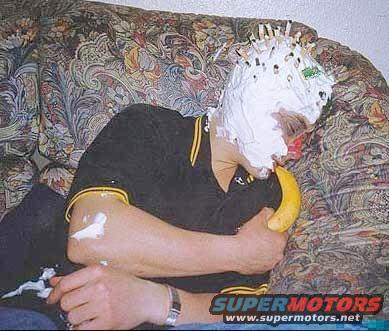Person with pie on face and banana in mouth, sitting on a patterned couch