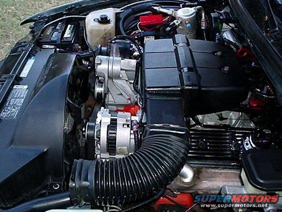 Engine bay with V8 engine, alternator, air intake hose, and radiator fan