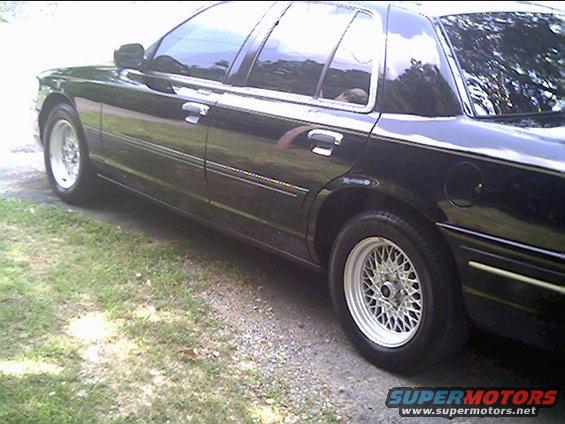 Black sedan, side view, showing chrome trim, wire wheels, and a gas cap