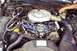 1985 Ford Crown Victoria LTD - The engine bay of a car, showing the V8 engine and various components, with a hand reaching in to work on the brake system.