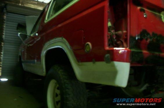 Rear quarter view of a red and white 1981 Ford Bronco in a garage