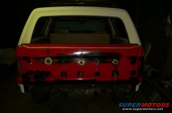 Red and white SUV rear view, showing bodywork in progress