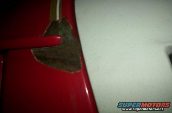 Red vehicle panel with a patch of rust and a yellow stripe