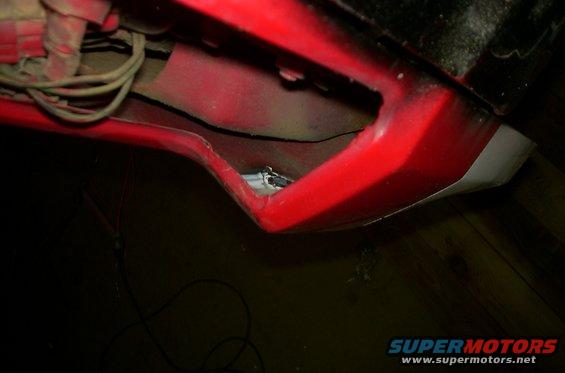 Red fender well with exposed wires and a glimpse of metal