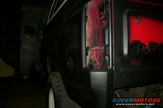 Black SUV rear quarter panel, taillight housing removed, red interior visible