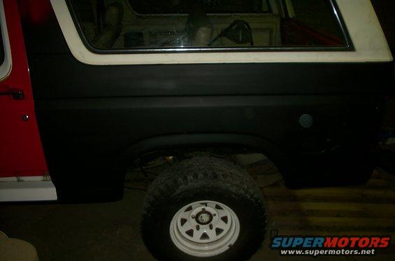 Side view of a Ford Bronco with black lower body panels and a red door