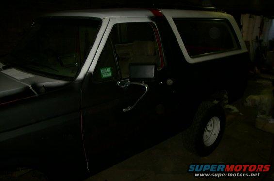 Black Ford Bronco with white roof and red stripe, side view
