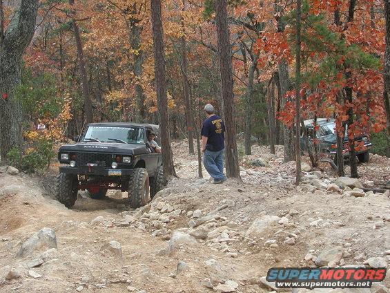 Black Ford Bronco with lifted suspension and large tires driving on a rocky trail