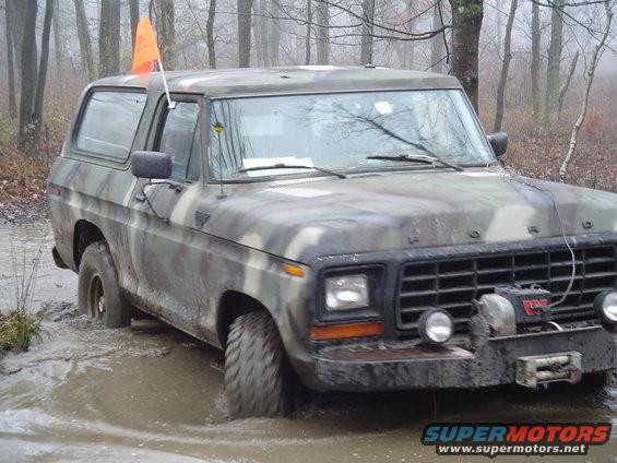 Camouflaged Ford Bronco stuck in mud, front view