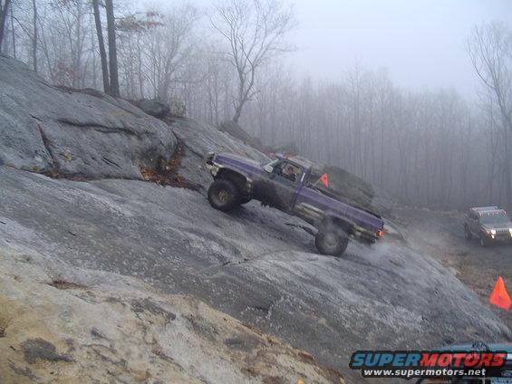 Purple pickup truck climbing a rocky hill with another SUV in the background