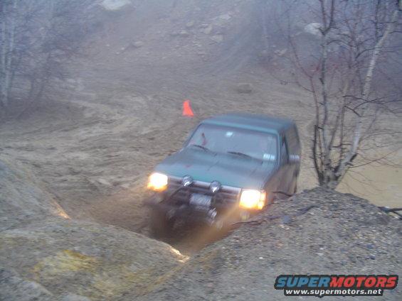 Green 1993 Ford Bronco navigating a muddy off-road course