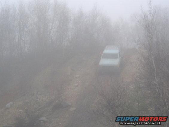 Light-colored SUV in fog on a dirt road