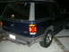 1996 Ford Explorer - The rear of a dark blue Ford Explorer SUV is shown at night, parked on a paved surface.