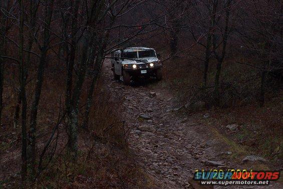 Hummer H1 driving on a rocky, wooded trail