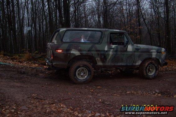 Camouflage 1979 Ford Bronco side view on dirt road