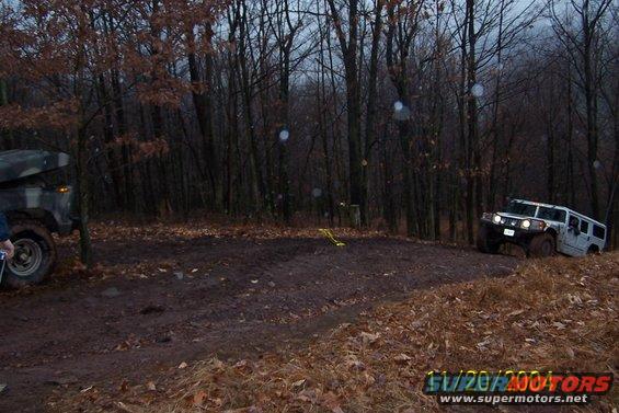 White Hummer H1 navigating a muddy off-road course with another vehicle partially visible