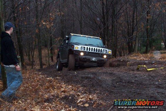 Black Hummer H2 driving off-road in mud and trees
