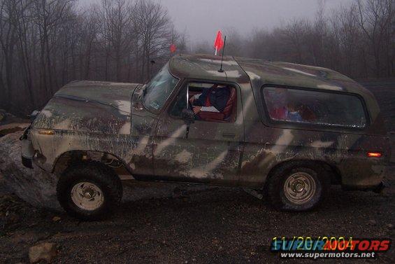 Camouflaged 1978 Ford Bronco on rough terrain, side view