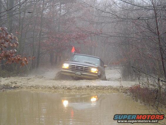 1995 Ford Bronco driving through mud, front 3/4 view