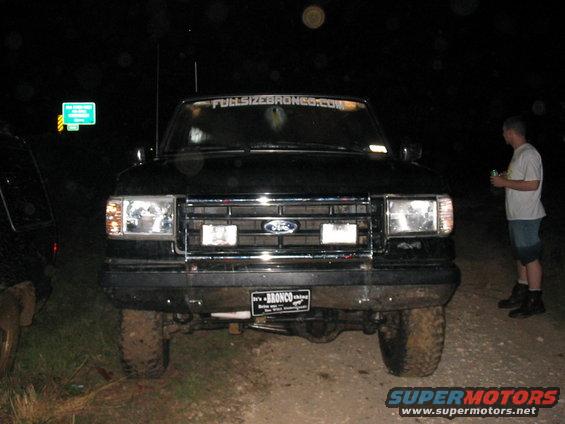 Black Ford Bronco front view, muddy tires, "It's a BRONCO" license plate, "FULLSIZEBRONCO.COM" windshield banner