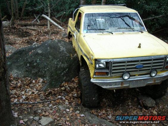 Yellow Ford truck with off-road tires navigating rocks