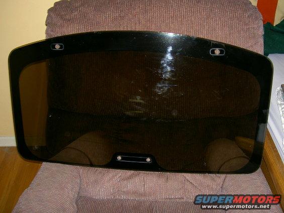 black rear window glass with two mounting points on top and one on bottom, resting on a chair