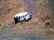 1979 Ford Bronco - A white SUV navigates a steep, rocky incline covered in dry grass and loose stones.