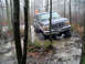 1979 Ford Bronco - A Ford Bronco navigates a muddy trail in a forest, with large tires splashing through the water.