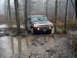 1979 Ford Bronco - A Hummer H2 tackles a challenging muddy trail surrounded by trees.