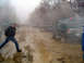 1979 Ford Bronco - A green SUV navigates a muddy track with other vehicles in the background, kicking up dust and mist.