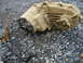1989 Ford Bronco - A dirty transfer case and its shifter are shown resting on a bed of gravel.