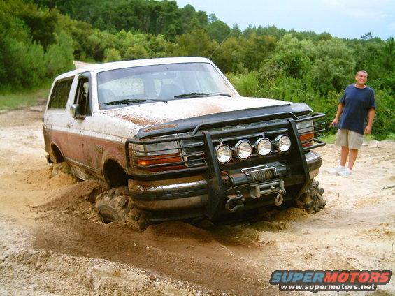 1993 Ford Bronco stuck in mud with a man standing nearby
