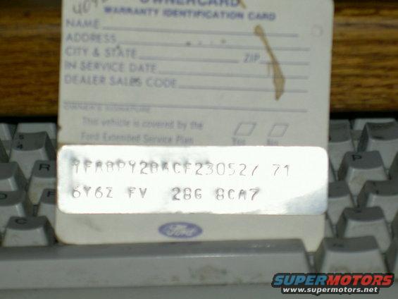 Warranty identification card with VIN and license plate details, resting on a keyboard