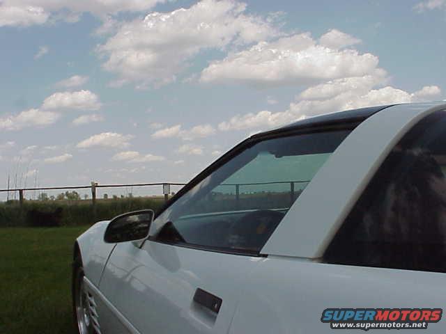 White coupe side view with black roof panel and a Supermotors logo