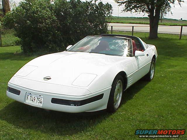 White convertible sports car parked on grass, front-left view. License plate reads F 749 754