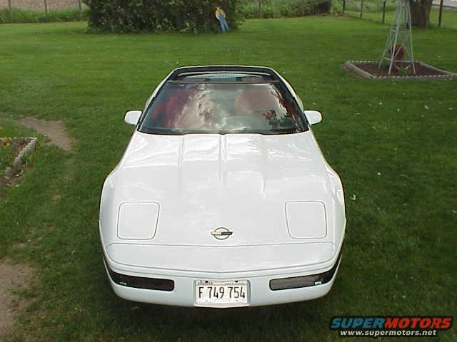 White 1994 Chevrolet Corvette parked on grass with a windmill in the background