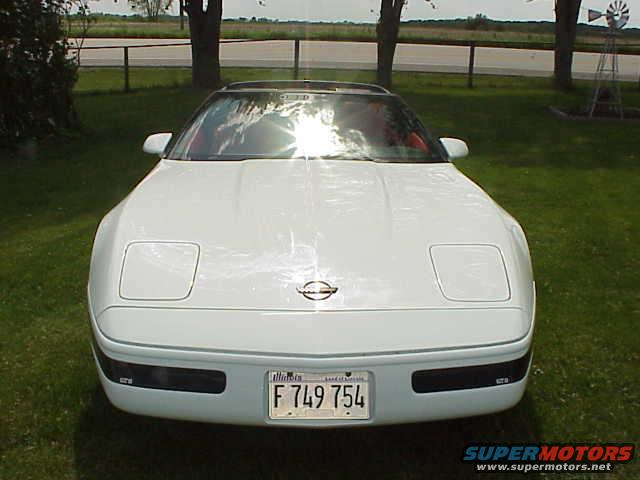 White 1994 Chevrolet Corvette with pop-up headlights down, parked on grass
