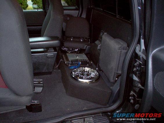 Truck interior showing custom subwoofer box and amplifier installed between the seats