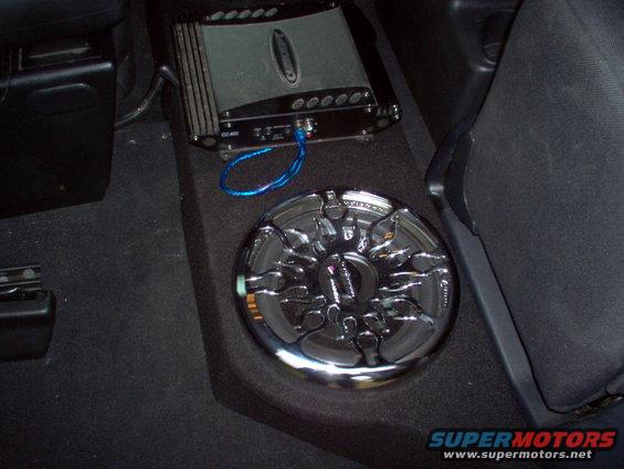 Car audio amplifier and chrome subwoofer installed in vehicle interior