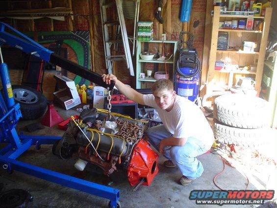 Engine being lifted by a blue engine hoist in a garage