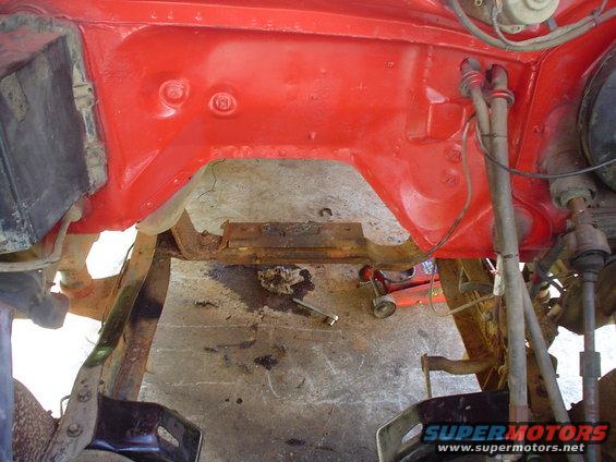 Red painted engine bay frame with rusty crossmember