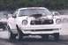 1976 Ford Mustang II - A white 1976 Ford Mustang II with racing stripes and an exposed engine sits on a drag strip.