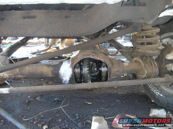 Differential housing with visible gears, suspension spring, and rusty metal components