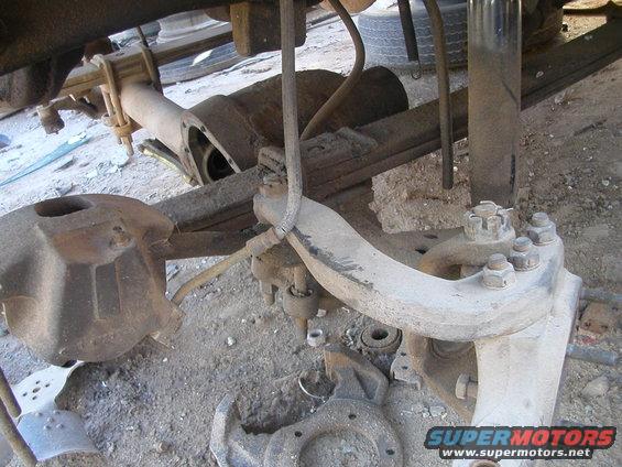 close-up of a vehicle's front axle components, including leaf springs and suspension parts